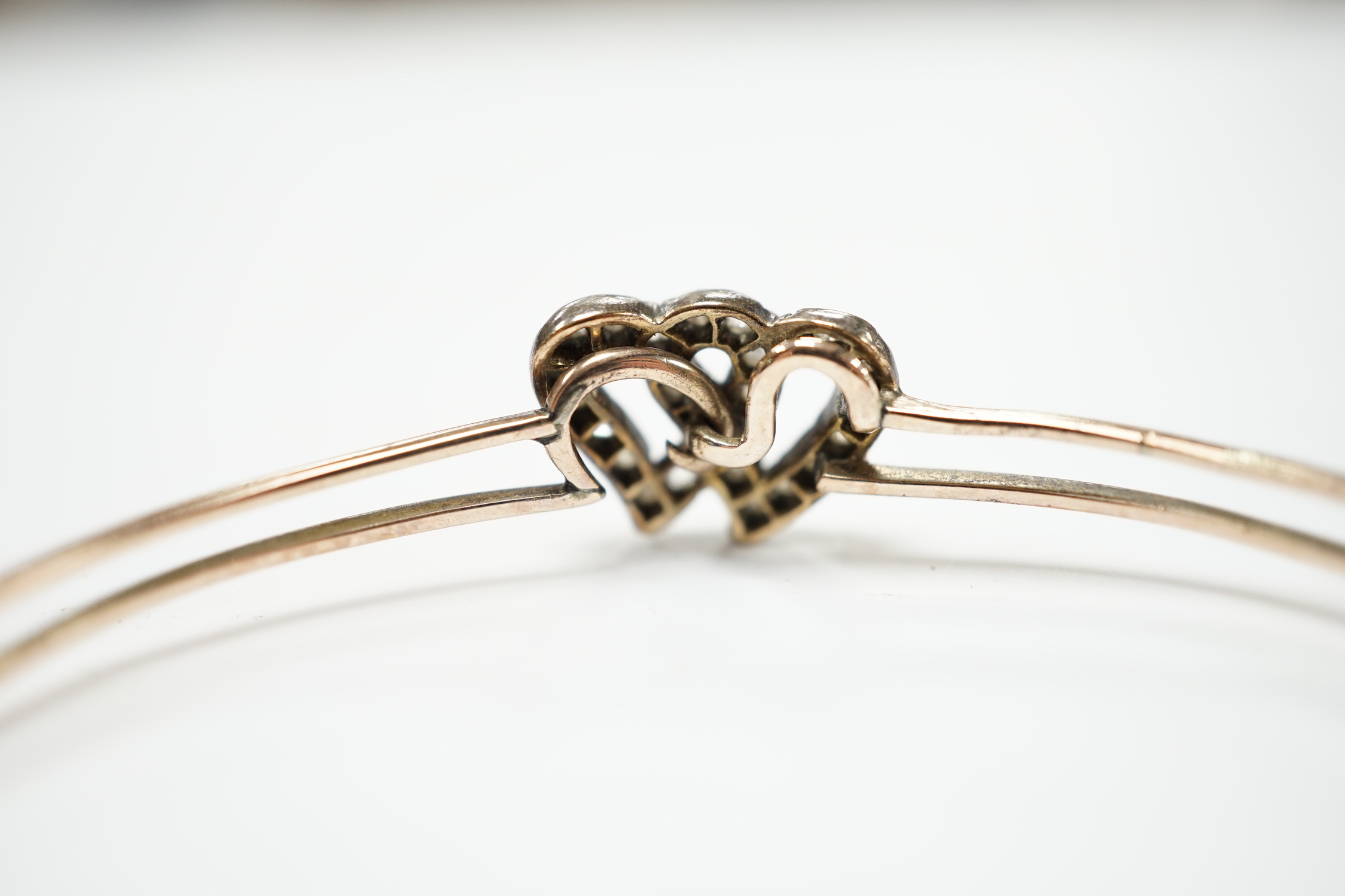 A late Victorian yellow metal and rose cut diamond set twin hearts bangle, gross weight 6.8 grams.